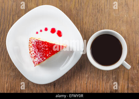 Un pezzo di torta e una tazza di caffè nero su uno sfondo di legno Foto Stock