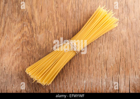 Materie spaghetti legato con una corda su un sfondo di legno Foto Stock