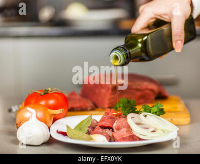 Lo chef si versa olio d'oliva sul filetto di carne Foto Stock