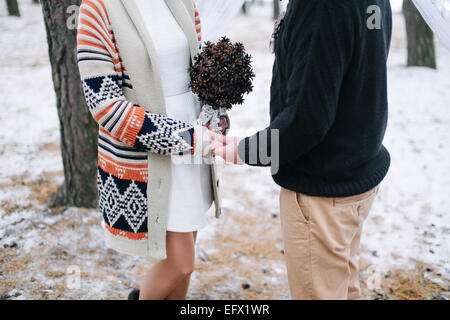 Sposa e lo sposo tenendo le mani durante l'inverno la cerimonia nuziale Foto Stock