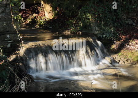 Flusso di spumanti e cascata che scorre attraverso il villaggio Foto Stock