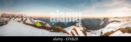 Panoramica del giovane maschio trekker montagna fotografare sullo smartphone nelle Alpi Bavaresi, Oberstdorf, Baviera, Germania Foto Stock