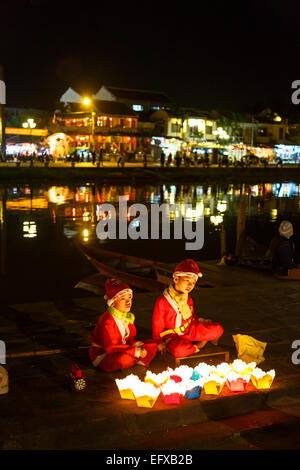 I bambini vestiti da Babbo Natale la vendita di candele galleggianti, Hoi An, Vietnam. Foto Stock