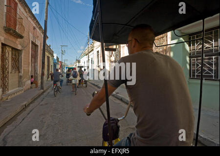 Vista orizzontale della bicitaxis cavalcando attraverso le strade di Camaguey, Cuba. Foto Stock