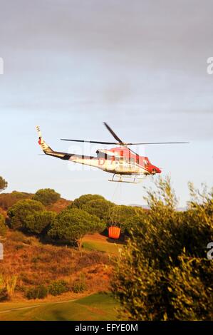 Bell 412 elicottero (registrazione N167EH) raccolta di acqua per la lotta contro gli incendi da un campo da golf lago, Cabopino Golf, Spagna. Foto Stock