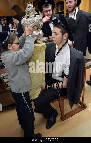 Un giovane religioso ragazzo ebreo che copre la Torah dopo una lettura alla mattina dei giorni feriali servizi in Brooklyn, New York Foto Stock