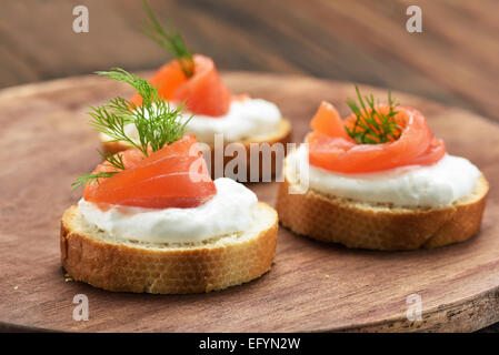 Panini con salmone sul tagliere di legno Foto Stock