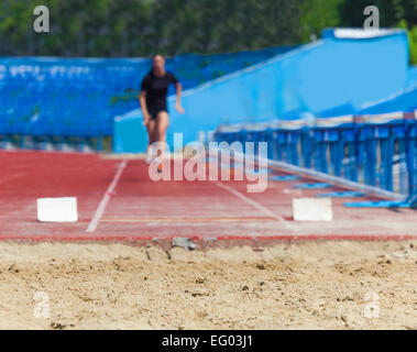 Atleta salta in lunghezza, sfondo sport Foto Stock