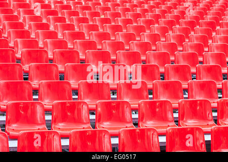 Righe vuote rosso brillante sedili in plastica in uno stadio Foto Stock