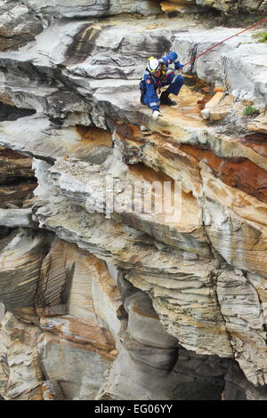 Un elemento maschio della speciale team operazioni all'interno del servizio ambulanza del NSW, conduce la discesa in corda doppia e rappelling formazione. Foto Stock