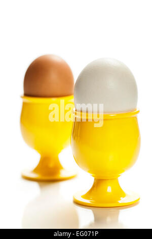 Uova in giallo eggcups isolato su bianco Foto Stock