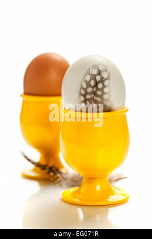 Uova in giallo eggcups isolato su bianco Foto Stock