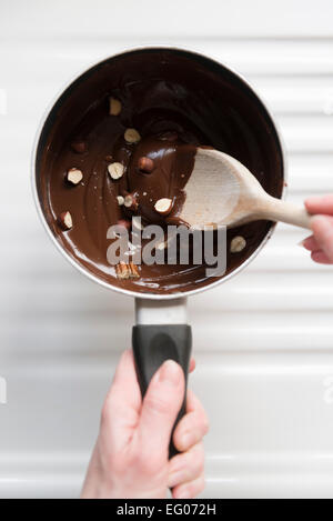 La cottura con il cioccolato fuso e il dado salsa in una pentola. Foto Stock