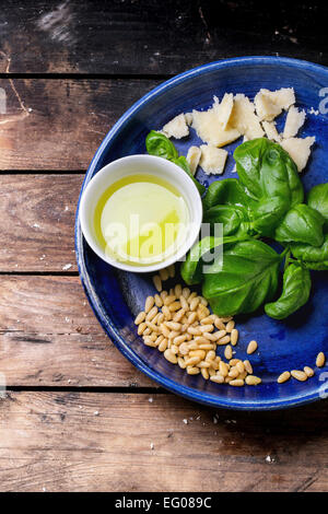 Ingredienti per il pesto di basilico servito su blu piastra ceramica su un vecchio tavolo di legno. Vista superiore Foto Stock