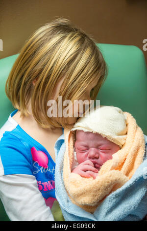 Ragazza giovane trattiene e baci nuovo baby fratello Foto Stock