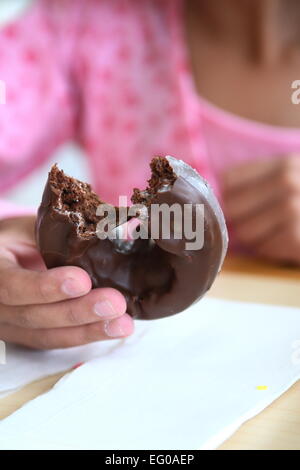 Tenendo il cioccolato ciambella con un morso prelevato Foto Stock