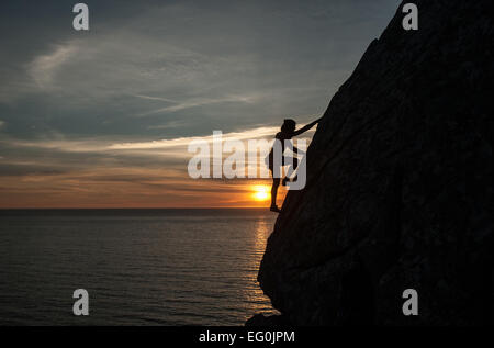 Silhouette di donna falesia di arrampicata al tramonto, Galizia, Spagna Foto Stock