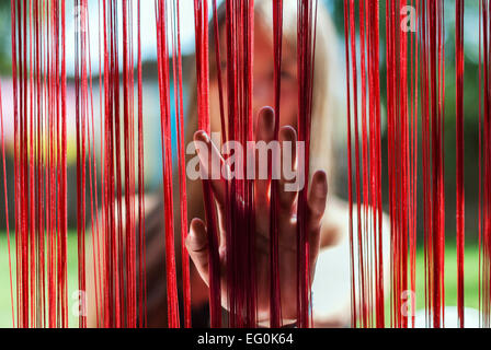 Donna che mette la mano attraverso una tenda frangia Foto Stock