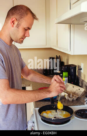 L'uomo cucinare uova fritte per la prima colazione Foto Stock