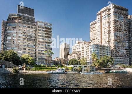 Blocchi a torre sulle rive del fiume Nilo, con barche in primo piano nella città del Cairo, Egitto Foto Stock