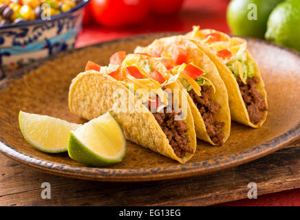 Una piastra di deliziosi tacos con calce, pomodori, lattuga e formaggio. Foto Stock