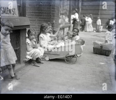 Antique c1900 fotografia, poveri bambini che giocano gli uni con gli altri, i genitori in background, Salem Street, Boston, Massachusetts, USA. Foto Stock