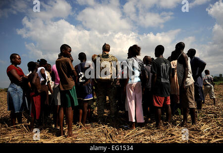 Stati Uniti Air Force Combat Controller e U.S. Esercito esploratori in terra in un campo e parlare con gli haitiani locale mentre si conduce nella zona di caduta i sondaggi per il futuro air drop siti su gennaio 24, 2010 a Port-au-Prince, Haiti durante il funzionamento risposta unitaria. Master Sgt. Jeremy bloccare rilasciato Foto Stock