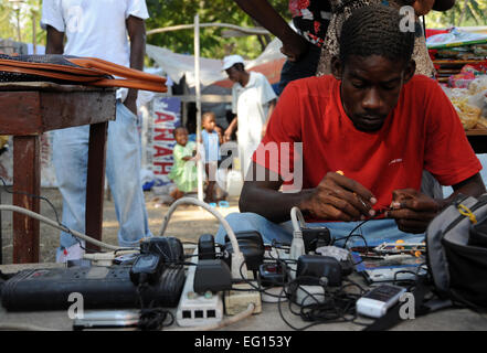 Un profughi haitiani uomo corregge i telefoni cellulari in una tendopoli vicino al Palazzo Presidenziale di Port au Prince, Haiti il 24 gennaio, 2010. Haiti è stata devastata da un terremoto di magnitudine 7.0 a gennaio 12, 2010 . Tech. Sgt. Prentice Colter rilasciato Foto Stock