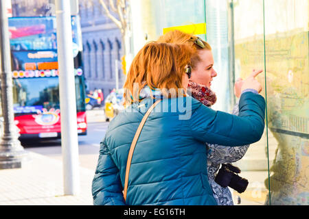 Due donna la consultazione di una mappa in una stazione degli autobus. Barcellona, in Catalogna, Spagna. Foto Stock