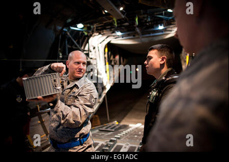 YOKOTA AIR BASE, Giappone --Tech. Sgt. Douglas Harper, 374 Manutenzione aeromobili squadrone battenti crewchief, prende un momento per attività di Mentor, insegnamento sua aviatori circa le differenze tra un ricevitore-trasmettitore e un generatore di unità di controllo qui Marzo 14. Il C-130 che giocano un ruolo cruciale nel soccorso in caso di catastrofe dovuta alla loro capacità di atterrare su piste di sporcizia e altre meno ideali condizioni di atterraggio. Il personale Sgt. Samuel Morse Foto Stock