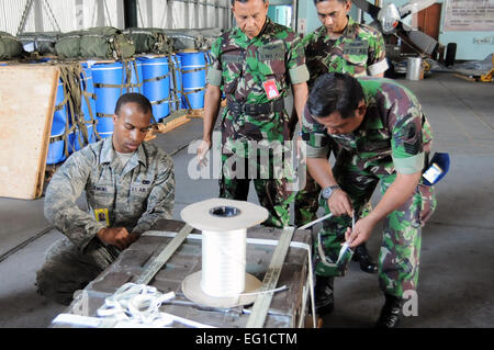 Stati Uniti Air Force Airman 1. Classe Brandon Jenkins, un rigger con la 374 disponibilità logistica squadrone di combattimento aereo di mobilità, funziona con un'aeronautica militare indonesiana rigger per costruire una a basso costo e bassa altitudine bundle 22 giugno 2011, durante una lezione di manovre in esercizio a far fronte ovest 11 a Halim Air Base, Indonesia. Il seminario di formazione, uno dei numerosi pianificate durante l'esercizio, è stato progettato per incoraggiare lo scambio di informazioni tra gli Stati Uniti e le forze indonesiane, e promuovere una migliore interoperabilità per le future missioni combinate. Il cap. Raymond Geoffroy Foto Stock