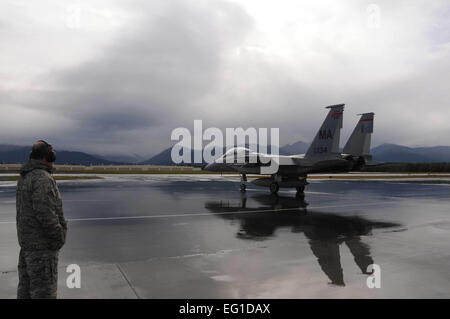 Stati Uniti Air Force Lt. Col. Chris Bigelow osserva un Air Force F-15 Eagle fighter aircraft dal Massachusetts Air National Guard il 104th Fighter Wing taxi verso il basso di una linea di volo il Agosto 5, 2011, prima del decollo mentre distribuito alla base comune Elmendorf-Richardson, Alaska, per la formazione. Bigelow è il comandante della 104th squadrone di manutenzione. Tech. Sgt. Anthony Mutti Foto Stock