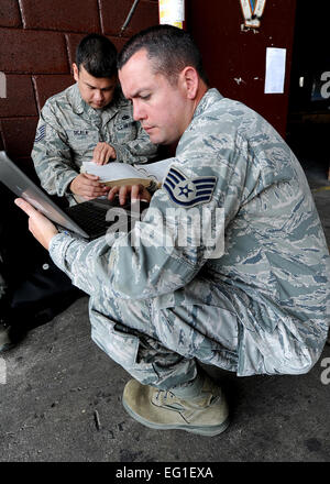 Stati Uniti Air Force Tech. Sgt. Ruben Sigala e Staff Sgt. Heric Llerena guardare in un manuale e una ricerca online per i dati tecnici su come installare correttamente un altimetro radar su un elicottero Febbraio 3, 2012, a Tegucigalpa, Honduras. Gli altimetri radar sono una componente di Terrain Avoidance Warning Systems che avvisa il pilota se l'aeromobile in volo è troppo bassa o se vi è un terreno in salita in anticipo. Tech. Sgt. Lesley acque Foto Stock