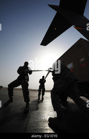 Stati Uniti Air Force aviatori dal 8 Expeditionary Aria Mobilità squadrone sezione rampa sterzare un generatore come esso è tirato in una C-17 Globemaster III 11 Febbraio, 2012. Il Avieri dell'aria sono specialisti di trasporto dal 8 EAMS sezione rampa, che carica gli aeromobili con carico dopo che il carico sezione di elaborazione ha preparato il carico per il trasporto. Il personale Sgt. Nathanael Callon Foto Stock