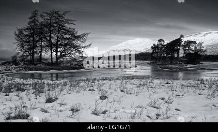 La prima luce del giorno getta un bagliore dorato sulle colline sopra Rannoch Moor presi dalle rive di un lago congelato Tulla Foto Stock