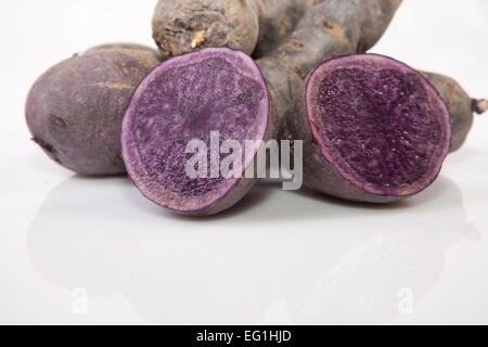 Affettato e tutta la porpora patate Vitelotte. Isolato su sfondo bianco Foto Stock