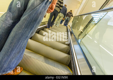 Adulti in sella a un escallator. Foto Stock