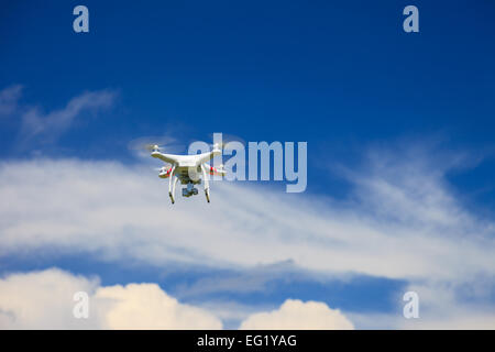 Una vista dal basso di un flying drone con una sospensione cardanica e fotocamera collegata. Drone, fotografia, volare, sorveglianza Foto Stock