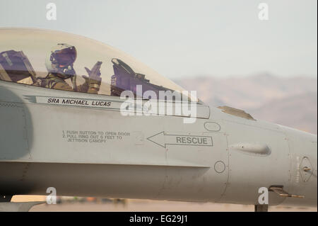 Un F-16 Fighting Falcon pilota dalla 55th Fighter Squadron, "combattenti", Shaw Air Force Base, S.C., visualizza il suo squadrone la consueta "pistole fino" gesto prima di una missione di addestramento Gen 29, 2014, presso la Base Aerea Militare di Nellis Nev. Bandiera rossa esercizi dare aviatori un opportunità di fare esperienza di combattimento realistici scenari di addestramento per preparare i futuri conflitti o guerre. Airman 1. Classe Joshua Kleinholz Foto Stock