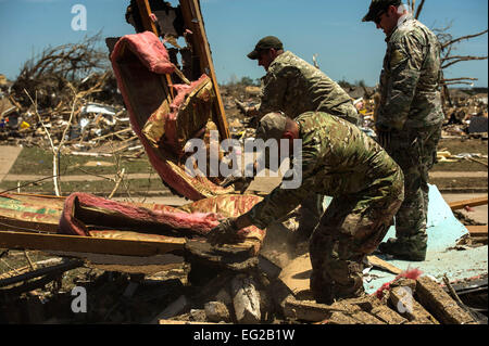 Stati Uniti Air Force Capt. Van Blaylock, anteriore, Tech. Sgt. Ben lago, centro e Tech. Sgt. Brandon bianco, torna, aiutare un Moore, Okla., residenti attraverso la ricerca di detriti per salvageable voci Maggio 22, 2013. Blaylock è assegnato all'aria 146supportano operazioni squadrone. Il lago e il bianco sono assegnati alla 138th Combat Training Squadron. Il personale Sgt. Jonathan Snyder Foto Stock