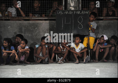 I bambini di osservare un gioco di pallacanestro tra Stati Uniti Avieri e Philippine avieri del 19 giugno 2014, a Buyong scuola elementare in Barangay Maribago, Lapu-Lapu City, Filippine. I membri del servizio hanno partecipato nel funzionamento unità pacifico 14-7, un 31-giorno progetto bilaterale che rinnovato utilities e costruito classi di una scuola. Il aviatori sono assegnati al 374 Ingegnere Civile squadrone a Yokota Air Base, Giappone. Il personale Sgt. Ambra E. N. Jacobs Foto Stock