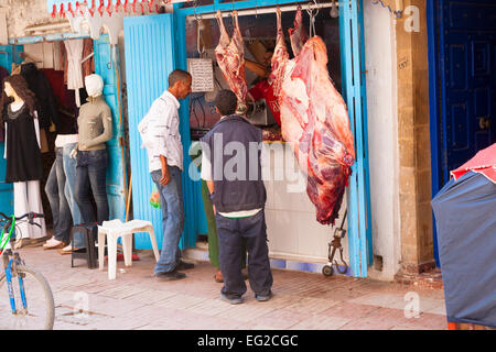 Due uomini parlavano tra loro in corrispondenza di una macelleria a Essaouira, Marocco Foto Stock