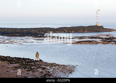 Metal detectorist sulle fangose sponde del fiume Severn a bassa marea, punto Beachley, fiume Severn, Gloucestershire, England, Regno Unito Foto Stock