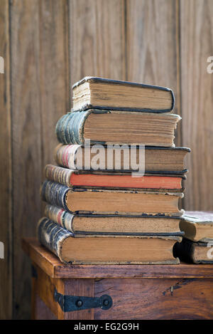 Pila di vecchi libri su uno scaffale di legno Foto Stock