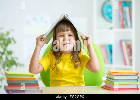 Preschooler kid ragazza con libro sopra la testa Foto Stock