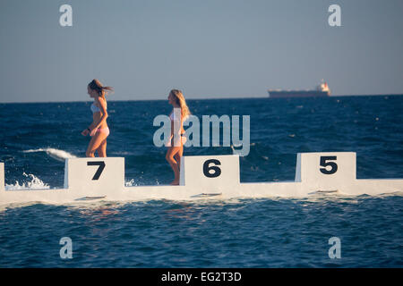 Merewether bagni di mare due giovani (adolescenti femmine) donne camminare a fianco della piscina Newcastle New South Wales NSW Australia Foto Stock