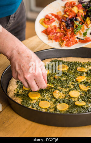 Donna immissione sauté di estate squash sulla sommità del multi-grain pizza al pesto Foto Stock