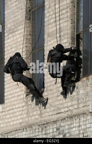 Suddivisione polizia anti-terrorismo durante un black tactical esercizi. Tecniche di corda. Situazione reale. Foto Stock