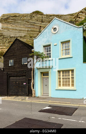 Vista di vecchi edifici costruiti proprio sotto le rocce in uno storico villaggio turistico di Hastings, East Sussex Foto Stock
