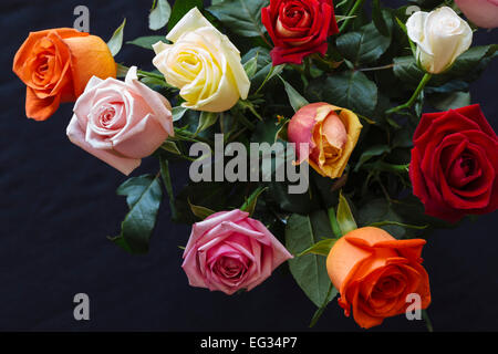 Mazzo di rose colorate in vaso contro la superficie scura Foto Stock